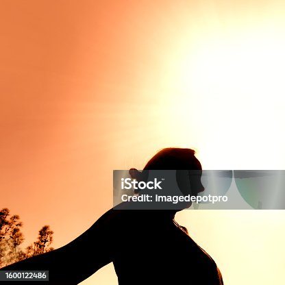 istock Silhouetted woman over glowing sun 1600122486
