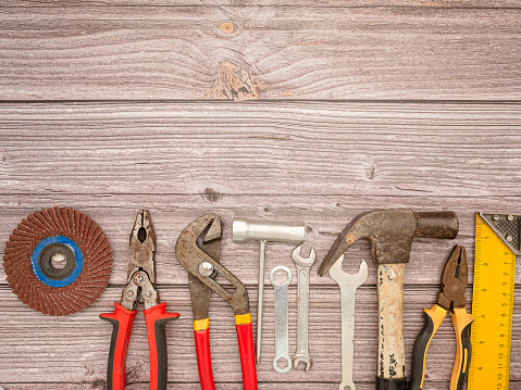 Construction tools, a hammer, screwdriver, screws, and pliers on a wooden table. Top view. Space for text