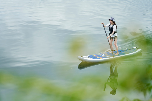 Japanese woman enjoying SUP on the river on holiday