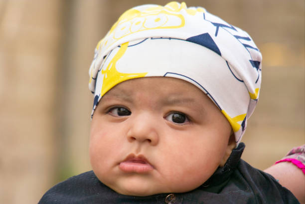 A heartwarming stock photo of a cute baby boy indoors, looking curiously at the camera. The image highlights soft lighting, innocent expression, and tender atmosphere — perfect for family, childhood, parenting, and lifestyle-themed projects.