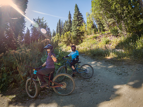 Eurasian daughter and Chinese mother mountain bikers resting at a switchback on a trail through an alpine forest in British Columbia, Canada.  Taken on a wearable camera.