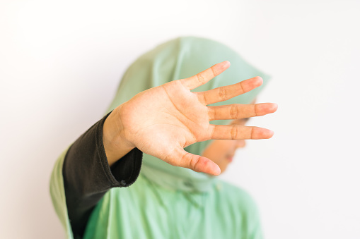 Asian Muslim young girl open palm to the camera, covering his face, stop gesture concept