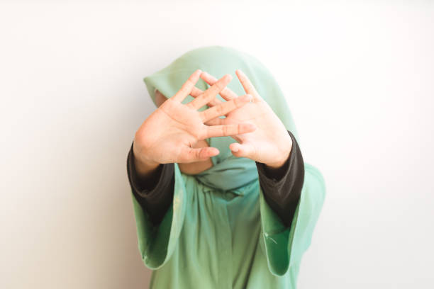 asiatisches muslimisches junges mädchen öffnet die handfläche in die kamera und bedeckt sein gesicht. stopp-geste - stop child stop sign child abuse stock-fotos und bilder