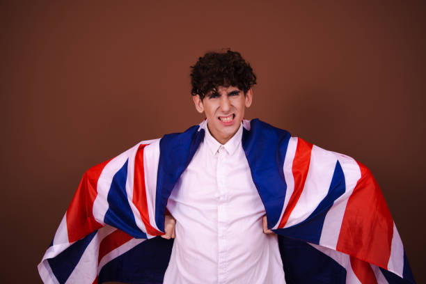 istock Young funny guy with british flag posing on brown background. 1600249989