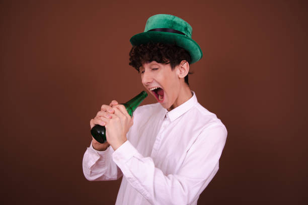 istock Young funny guy with a beer posing on a brown background. 1600255175