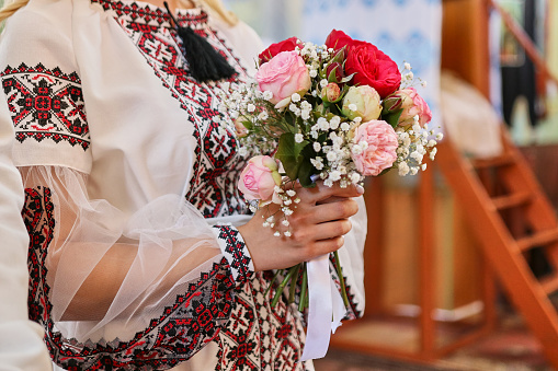 The girl in an embroidered shirt holds a beautiful bouquet of flowers.