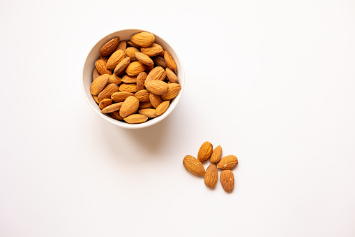 bowl with tasty almonds on white background, top view