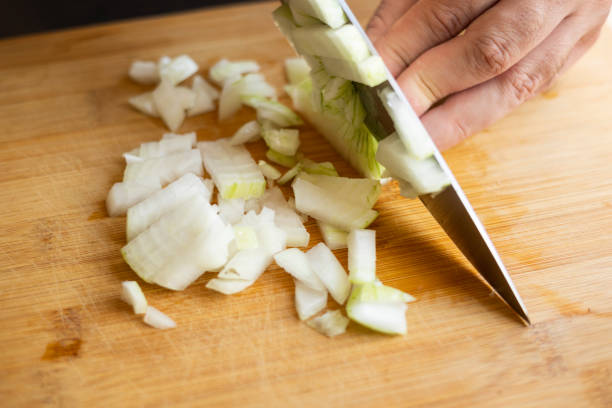 istock man hands cutting onion close up on wooden board at home kitchen 1600295578