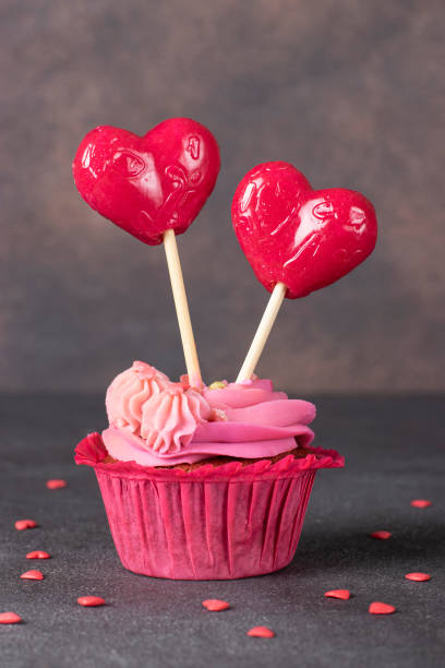 istock Cupcake with pink cream decorated with heart-shaped lollipops 1600312048