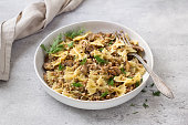 Traditional Jewish dish kasha varnishkes: buckwheat, pasta, champignon mushrooms, fried onions with herbs on a gray textured background, vegan food