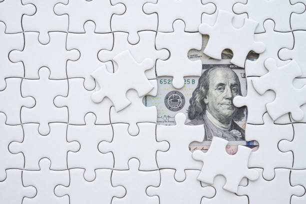 istock Benjamin Franklin president on US dollar banknote under unfinished white jigsaw puzzle. 1600345011