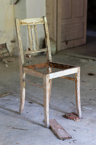 an old dirty broken wooden chair in a lost place
