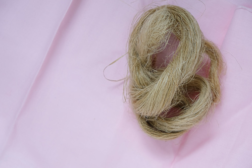 Fibers of natural uncolored flax or hemp, tow, close-up. Pink canvas. Growing demand for natural fibers.