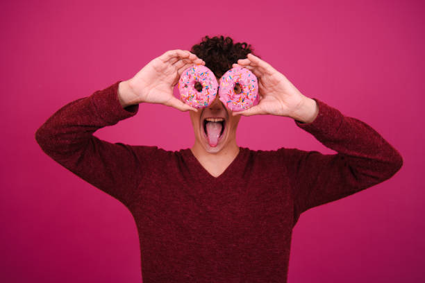 istock Young attractive guy eats pink donuts. Delicious breakfast and good vibes. 1600371172