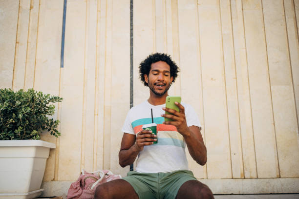 istock Man enjoying being alone sitting on park bench drinking coffee from disposable cup and using his mobile phone 1600376283