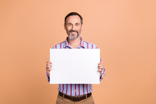 Portrait of cheerful friendly man toothy smile arms hold demonstrate empty space proposition poster isolated on beige color background.