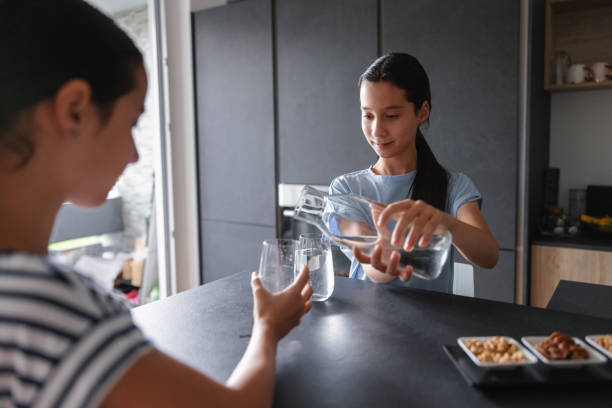 istock A Young Girl Is Serving Some Water Inside A Glass Over A Table At The Kitchen 1600397197