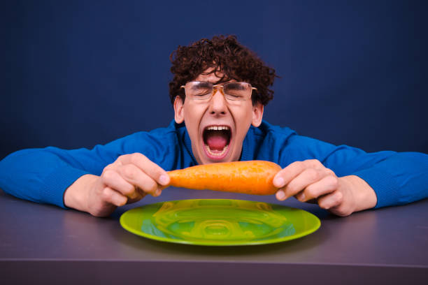 istock Funny silly guy eats carrots. Diet and healthy lifestyle. 1600417890