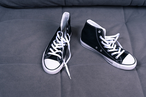 new youth sneakers with lacing lie on the home sofa. Trendy fashionable casual concept. High quality photo