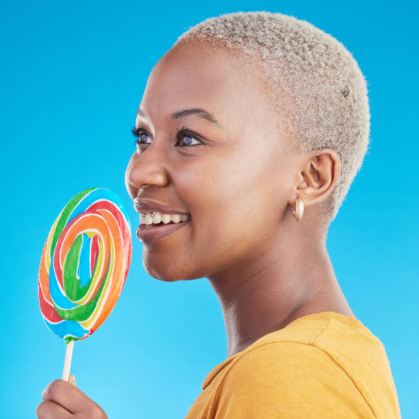 istock Lollipop, thinking and a woman with candy in studio for sweets, rainbow and creative idea. Profile of happy black female person isolated on a blue background with sugar, freedom and smile or color 1600428281