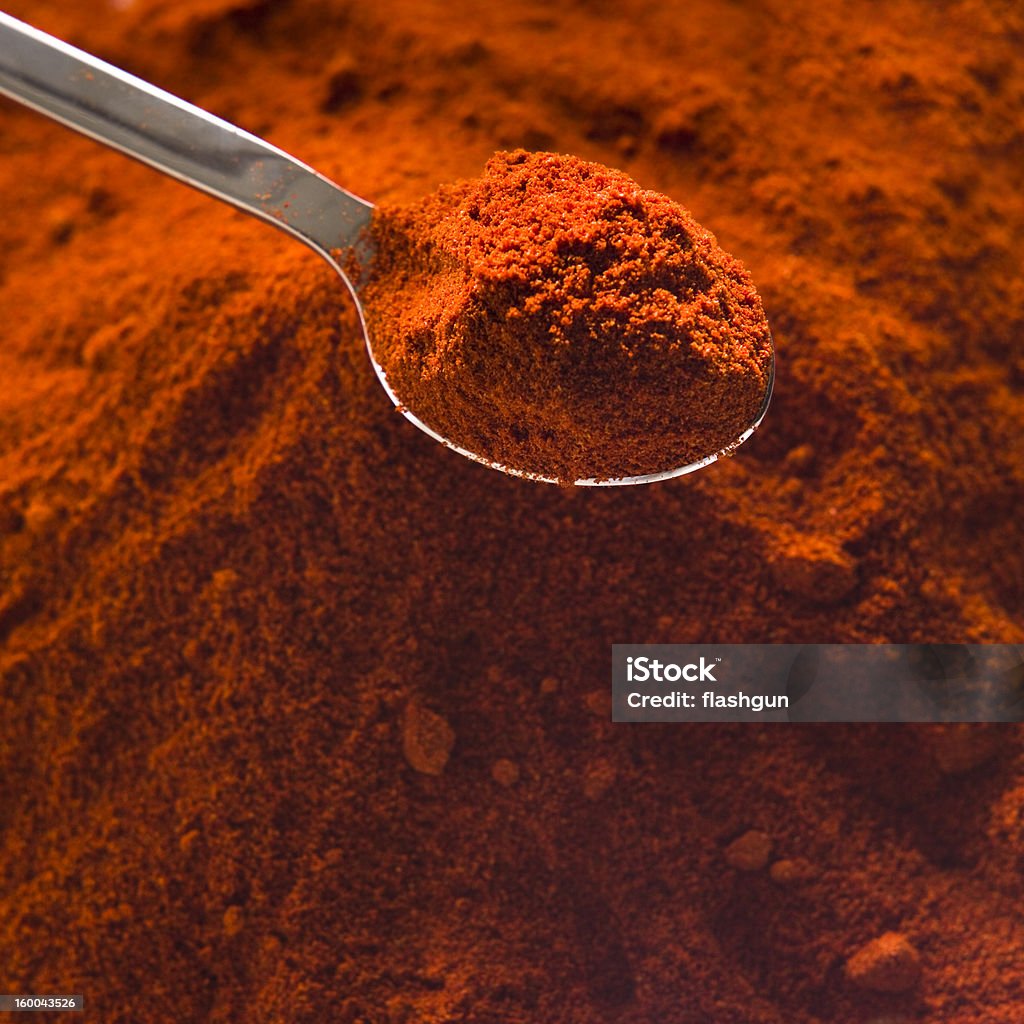 chili powder Pile of heaped chili powder with silver tea spoon Chili Pepper Stock Photo