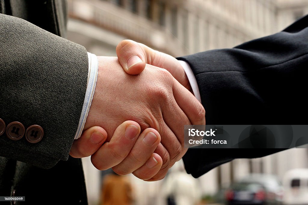 handshake handshake on a street, blurry buildings in the background Adult Stock Photo