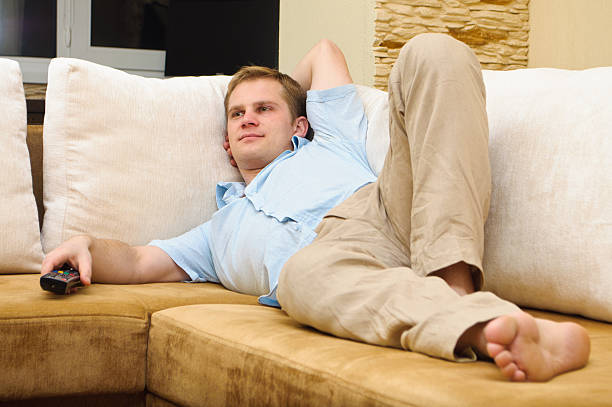 istock Man lying on sofa watching TV at home. 160045988