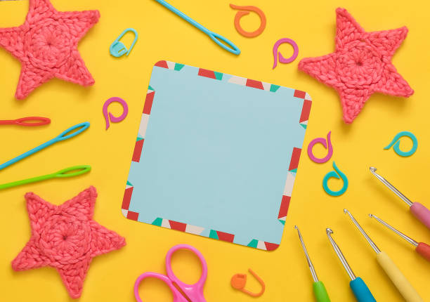 istock Empty blue card with crochet tools, crochet pink stars on a yellow background. Top view. Copy space. 1600463283