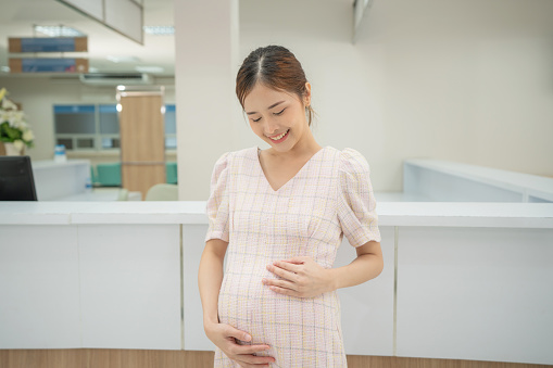 Asian Pregnant middle aged mother portrait. Pregnant happy Woman touching her belly, caressing her belly and smiling close-up. Healthy Pregnancy concept.