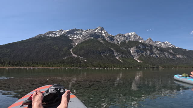 POV of woman paddle boarding (SUP) on mountain lake