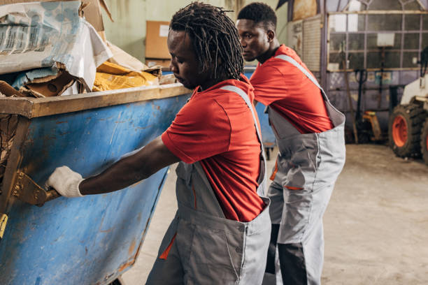 istock Two workers in recycling centre moving big dumpster with paper 1600467573