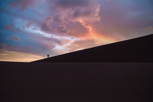 A scenic view of a hiker in the Namib desert at sunrise