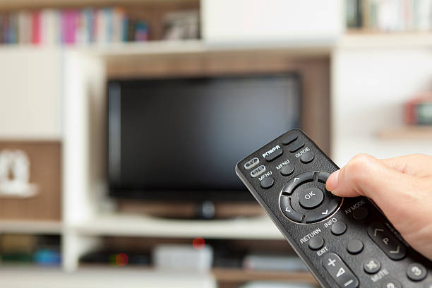 istock hand holding TV remote control toward television 160048578
