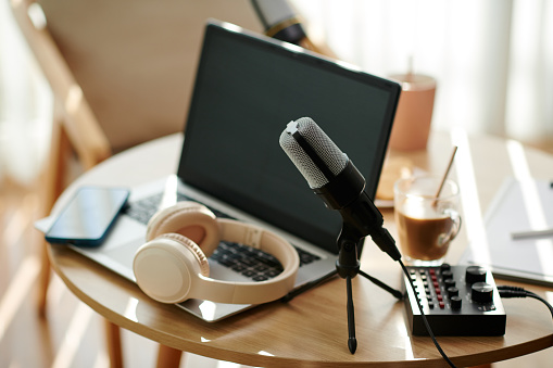 Microphone, laptop and headphones on desk of podcaster