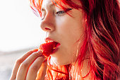 girl with red hair eats delicious ripe strawberries