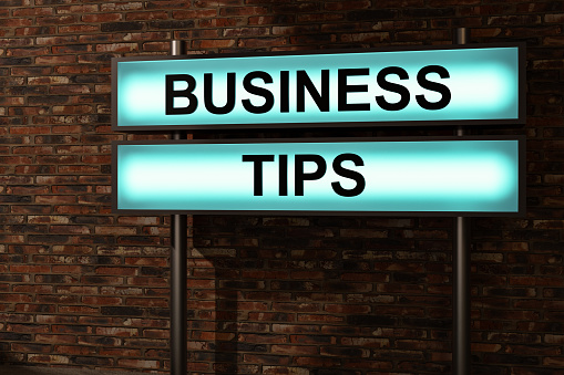 Business tips. Black letters on a blue illumintaed light box, red brick wall. Advice, guideline, rule, strategy, hint, instruction, procedure, control, organization. 3D illustration