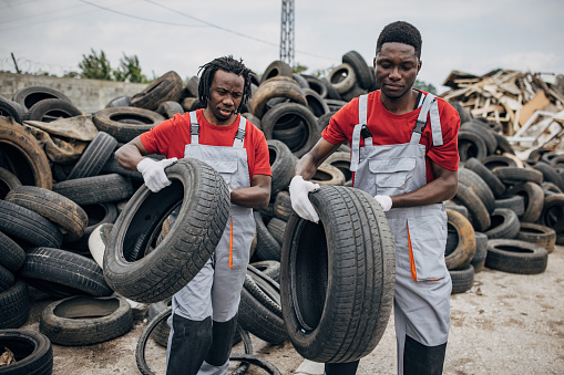 Two workers sorting rubber wheels at the recycling center