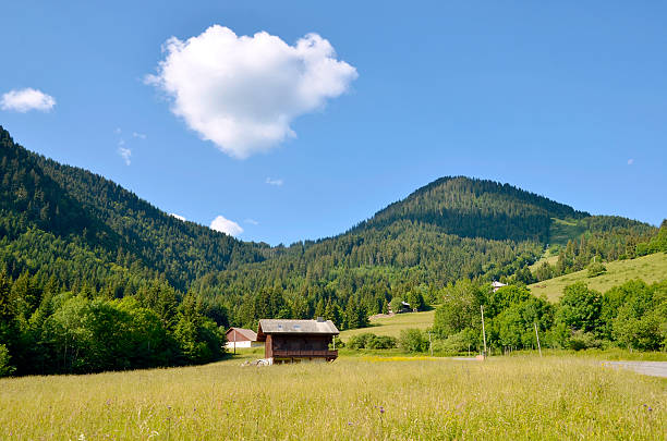 Mountains near of village Bonnevaux in the French Alps with a big white cloud in the blue sky. The Haute-Savoie department in the Rhône-Alpes region in south-eastern France.