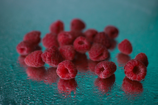 ripe juicy summer raspberries with water drops on a wet mirror surface. for advertising screensavers, flyers, business cards, postcards, etc.