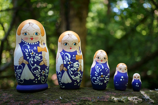 Beautiful nesting dolls on the background of branches and leaves.