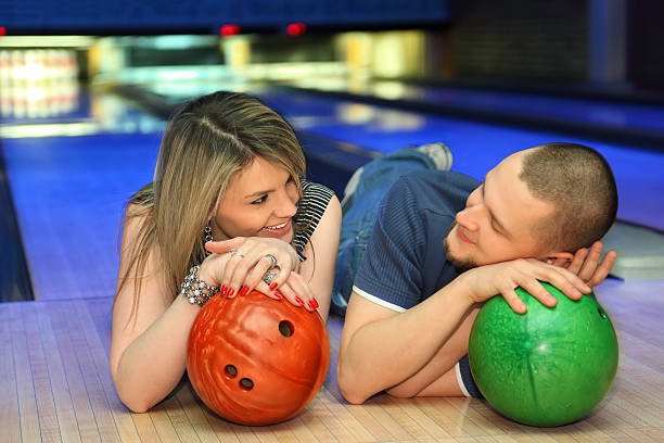 istock Fellow and girl lie leaning against balls for bowling 160051549