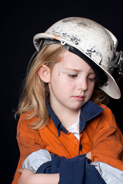 Young girl in coal miner hart hat and safety clothing stock photo