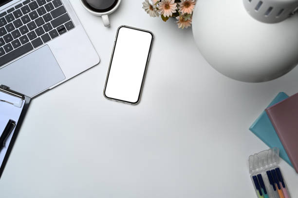 istock Top view of smartphone with empty screen, laptop and coffee cup on white table 1600529040