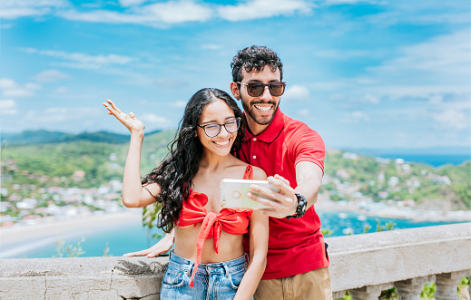 Smiling tourist couple taking a selfie at the viewpoint of San Juan del Sur. Happy Young tourist couple taking a selfie in a beautiful viewpoint