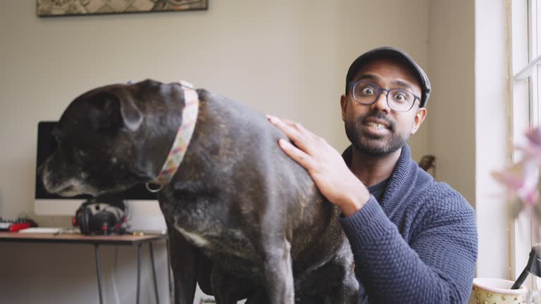 Smiling young man petting his dog at home