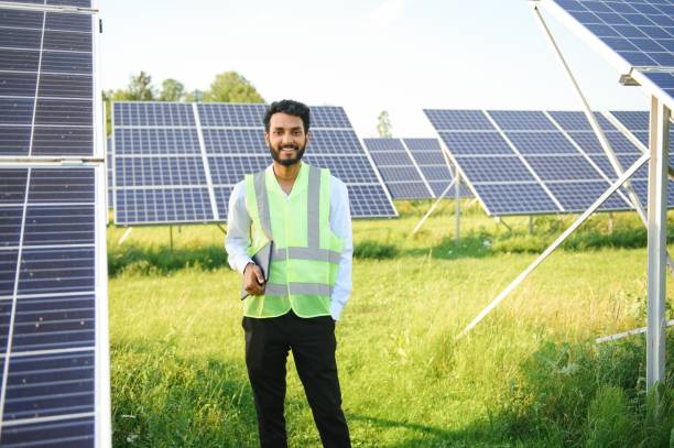 istock Portrait young indian technician or manager wearing formal cloths standing with solar panel. renewable energy, man standing crossed arm, copy space 1600556630