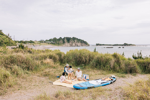 Japanese family shares a beach picnic, the scene capturing their connection and the joy of spending quality time by the sea.