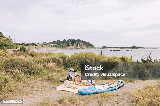 istock Japanese family relaxes with a picnic on the sand, making memories by the shore 1600558260