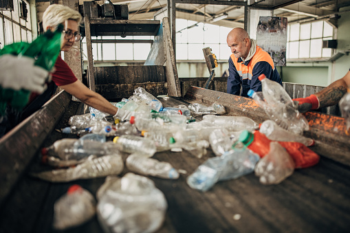 Group of workers at the recycling centre sorting plastic waste ad preparing for recycling
