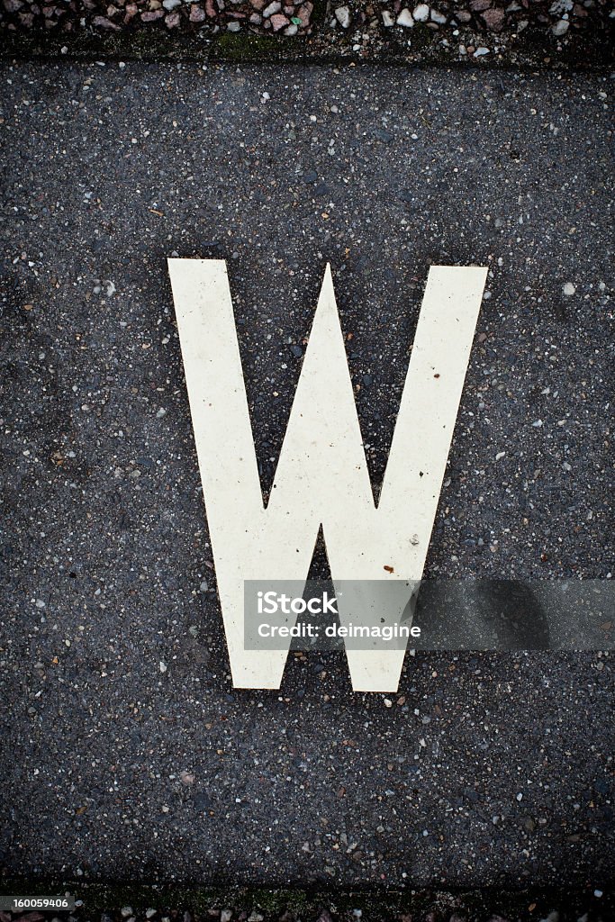 White Letter W on the Road Asphalt. Asphalt background with white letter painted.  Alphabet Stock Photo